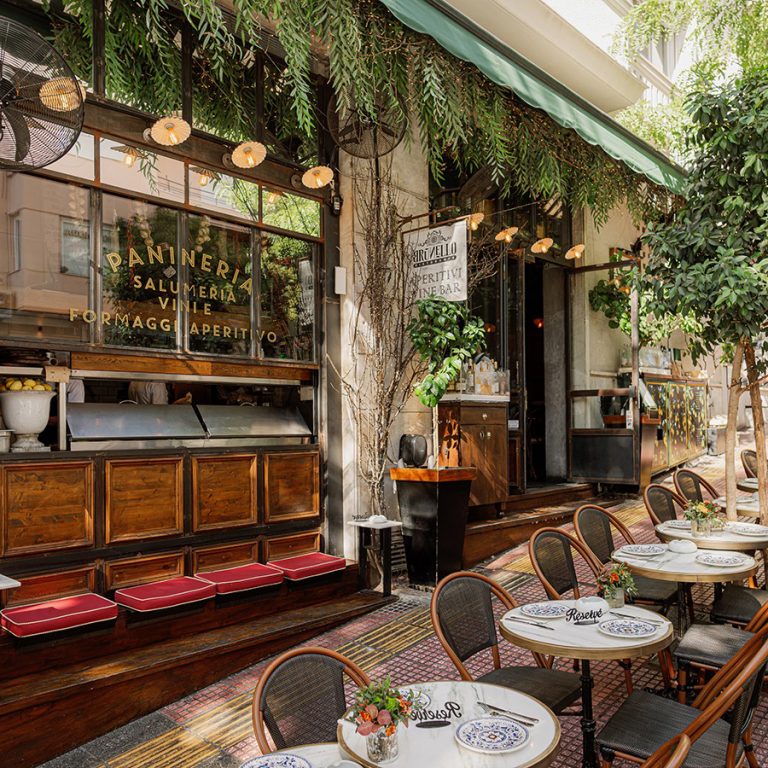 Outdoor tables of Brunello in Kolonaki with wine glasses and aperitivo plates.